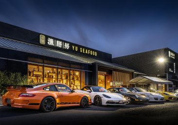 Elegant PCC Annual Members Gala at Yu Seafood: members in formal attire toasting with whisky glasses amid Porsche displays, fine dining tables, prizes, and recognition awards.